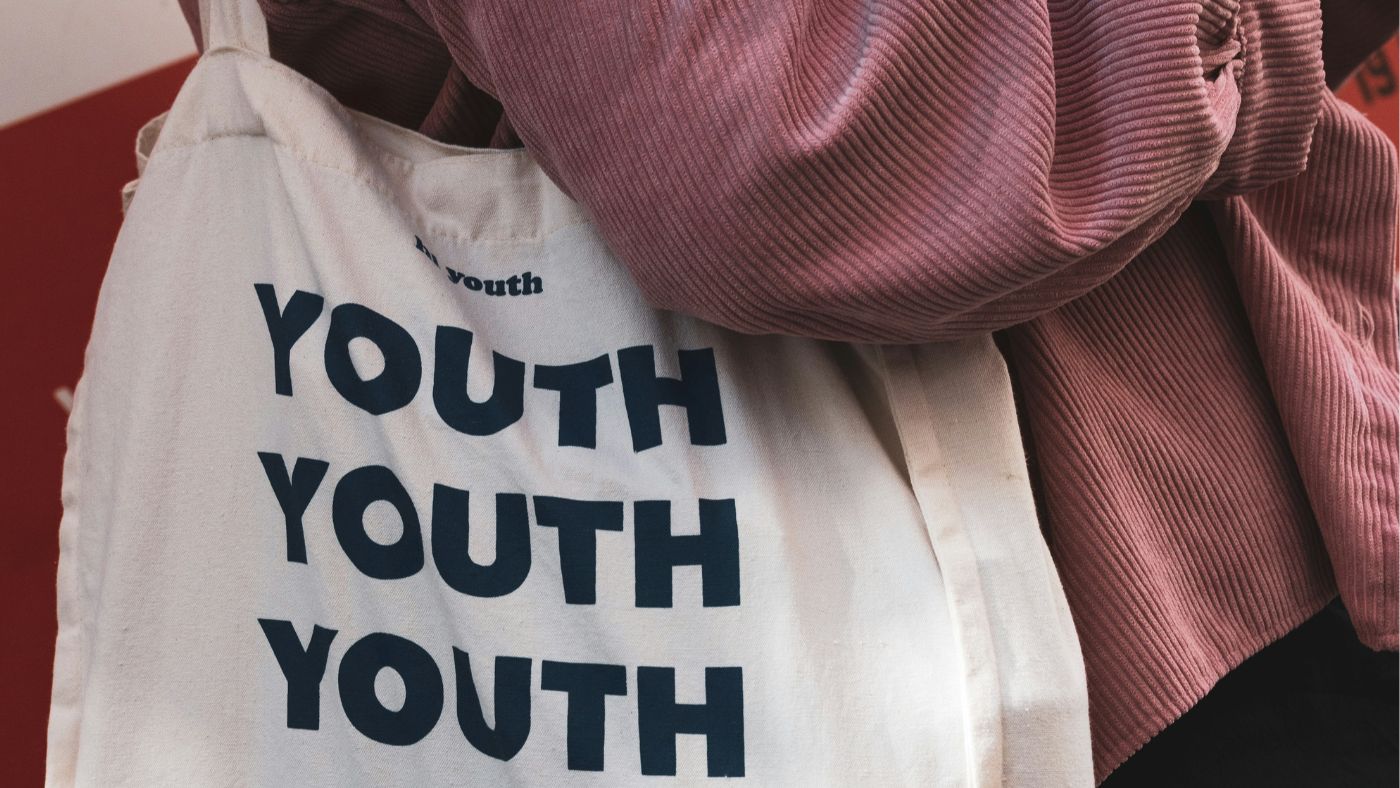 Netzwerk Jugendparalmente_FR_Website Person trägt weiße Stofftasche mit dem Schriftzug YOUTH YOUTH YOUTH.