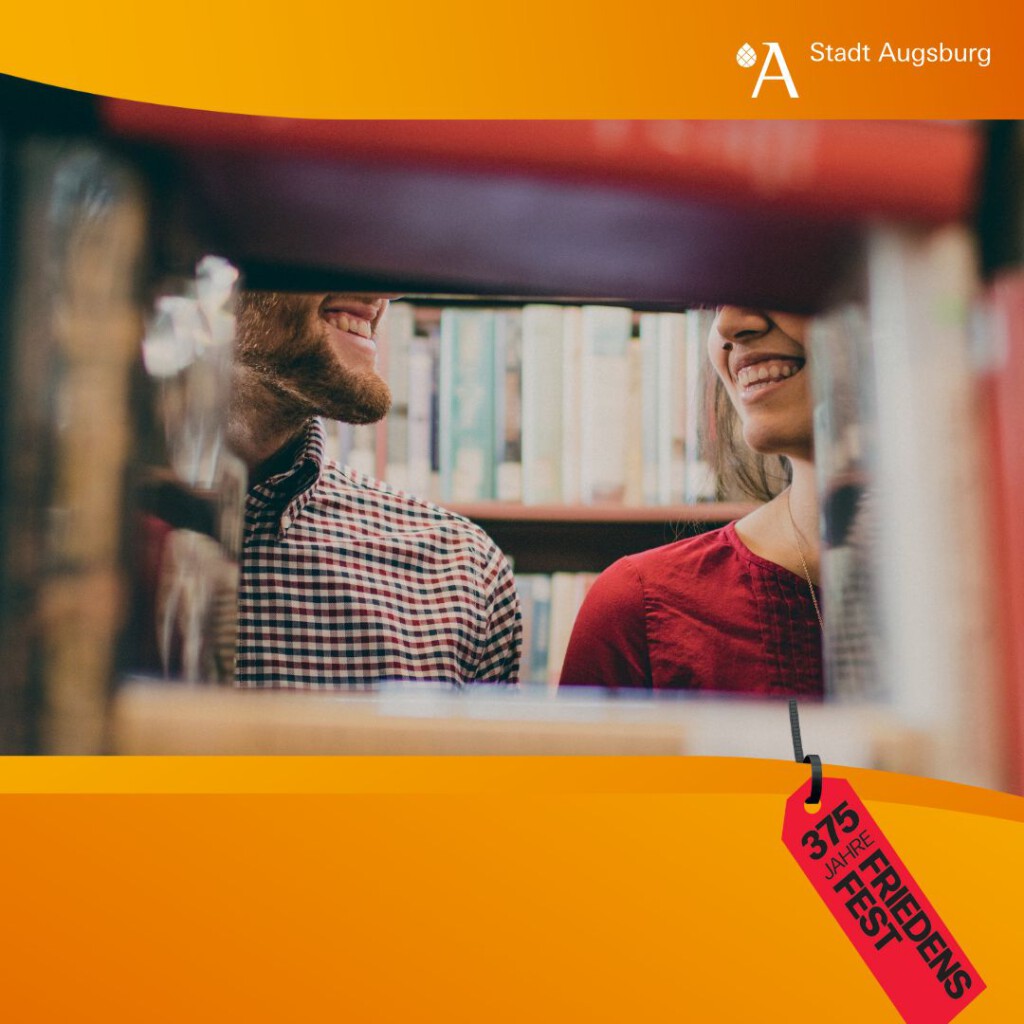 Durch eine Lücke im Bücherregal sieht man zwei Personen vom Schulter- bis Kopfbereich bis auf die Augen, sich anlächeln.