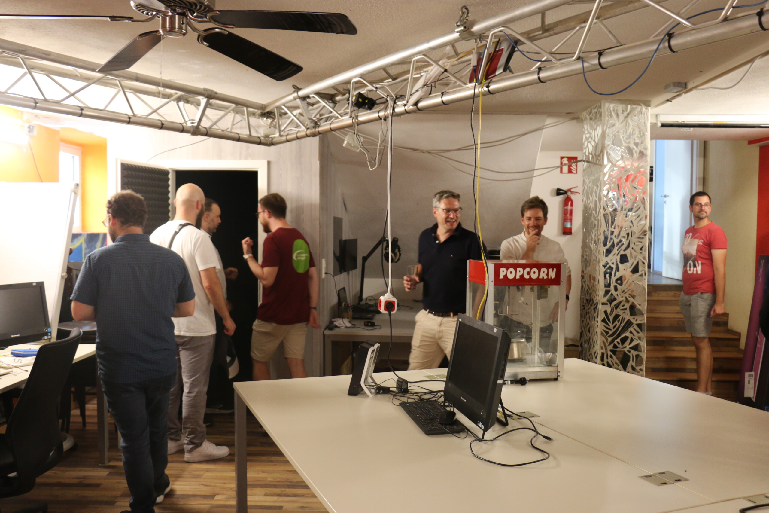 Mehrere Männer besichtigen eine Kellerraum im Jugendhaus Wertigen, wo Bildschirme, Podcast-Equipment, eine Popcornmaschine und große Schreibtische stehen